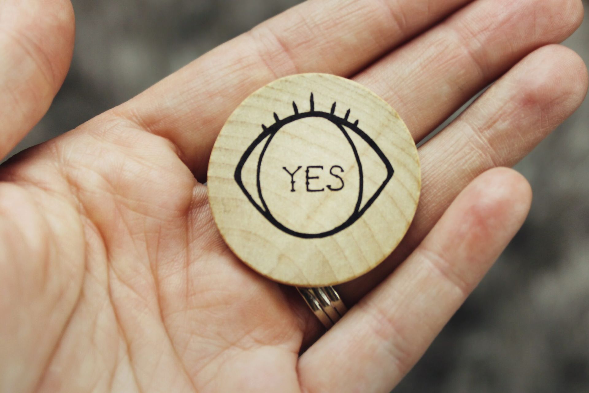 hand holding a wooden chip with the word 